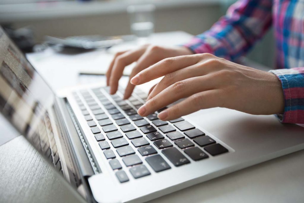 Cropped View of Hands Typing on Laptop Cropped view of person hands typing on laptop computer